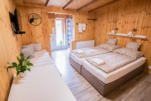 two beds in a room with wooden walls at Volcz Családi Birtok in Ajka