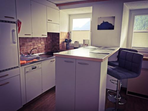 eine Küche mit weißen Schränken, einer Spüle und einem Stuhl in der Unterkunft Haus Crestas in Samnaun