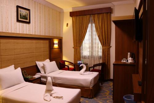 a hotel room with two beds and a swan on the bed at Diyar Taiba Hotel in Medina