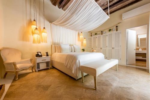una camera con un letto bianco e una sedia di Casa Diluca Cartagena Hotel Boutique a Cartagena de Indias