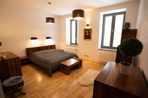a bedroom with a bed and a table and windows at Black Field Apartment in Brno
