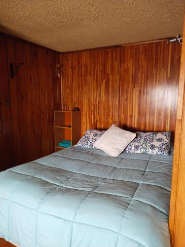 a bedroom with a large bed with wooden walls at lotus shared-house in Puerto Montt
