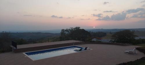 a swimming pool with a sunset in the background at Chalés da Cuesta in Pardinho
