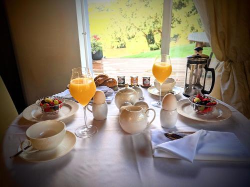 a table with breakfast foods and glasses of orange juice at Worralls Grove Guest Farm House in Bewdley