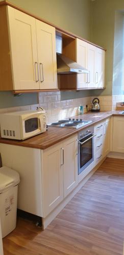 a kitchen with white cabinets and a microwave at Quarry street Hamilton in Hamilton