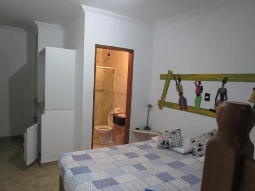 a bedroom with a bed and a bathroom with a toilet at Hotel Iracemar - Econômico in Guarujá