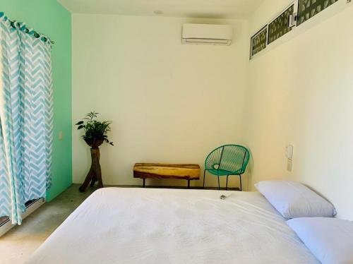 a room with a bed, chair, table and a lamp at Paziflora Hostel in Puerto Escondido