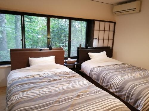 two beds sitting in a room with windows at c o p s e h a u s-Vacation STAY 97230 in Azumino