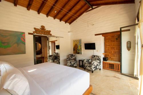 a bedroom with a white bed and two chairs at Quinta Ascensión Hotel Boutique Only Adults in Malinalco