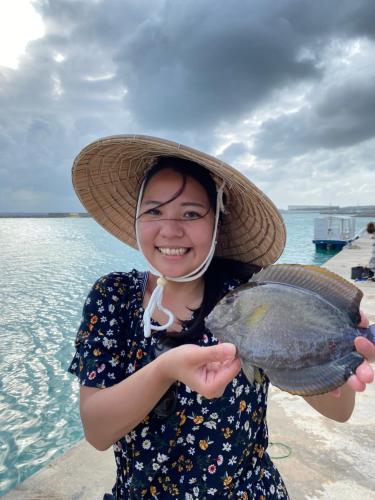 una mujer con un sombrero de paja sosteniendo un pez grande en ゲストハウス喜舎場 en Isla Ishigaki