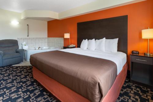 a hotel room with a large bed and a chair at AmericInn by Wyndham Wausau in Weston