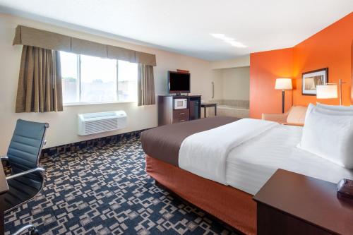 a hotel room with a large bed and a desk at AmericInn by Wyndham Wausau in Weston