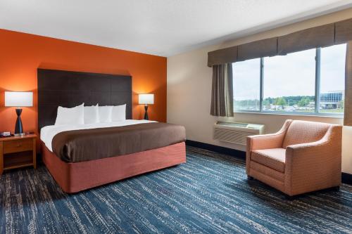 a hotel room with a bed and a chair at AmericInn by Wyndham Wausau in Weston
