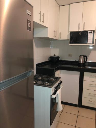 a kitchen with a stove and a refrigerator at Qurpawasi in Lima