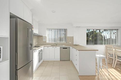 a kitchen with white cabinets and a stainless steel refrigerator at Husky 56 Beachfront Villa's - great location on the beach in Huskisson