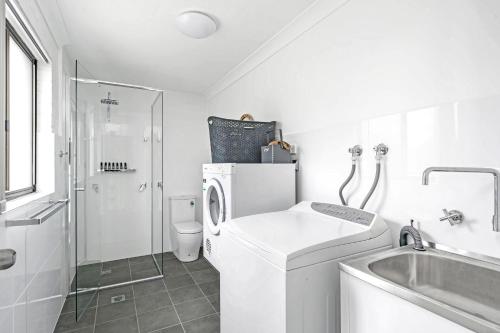 a white bathroom with a washing machine and a sink at Husky 56 Beachfront Villa's - great location on the beach in Huskisson