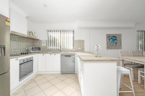 a kitchen with white cabinets and a table and a counter at Husky 56 Beachfront Villa's - great location on the beach in Huskisson