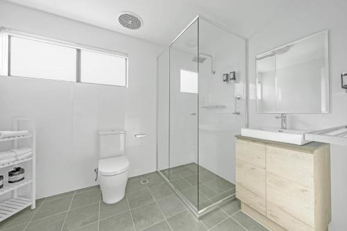 a white bathroom with a toilet and a shower at Husky 56 Beachfront Villa's - great location on the beach in Huskisson