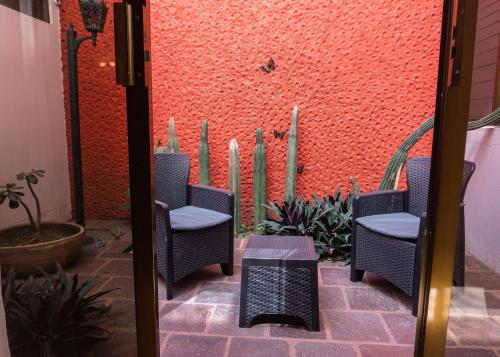 a patio with wicker chairs and a red wall at Hotel Casa Pereyra in Oaxaca City
