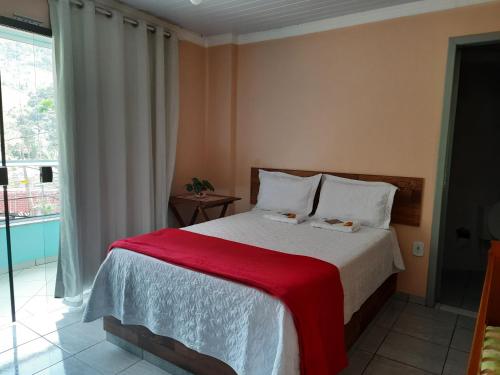 a bedroom with a bed with a red blanket at Cobertura das Montanhas in Domingos Martins