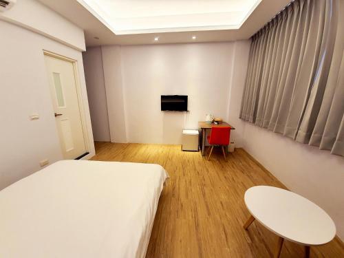 a bedroom with a bed and a table and a tv at 站前夥伴旅宿 in Hualien City