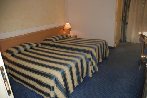 a hotel room with two beds with striped sheets at Hotel Continental Brescia in Roncadelle