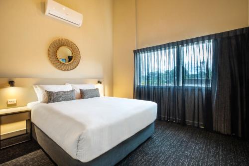 a bedroom with a large bed and a window at Nightcap at Manhattan Hotel in Ringwood