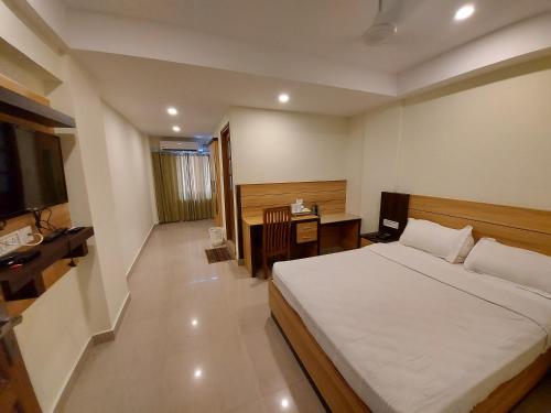 a bedroom with a bed and a desk in it at Hotel Sree Gokulam Apartments in Guruvāyūr