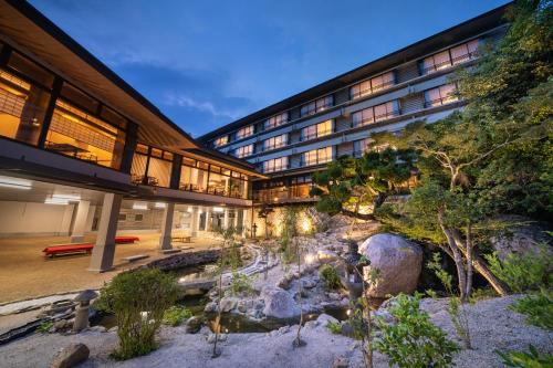a building with a river in front of it at Miyajima Grand Hotel Arimoto in Miyajima