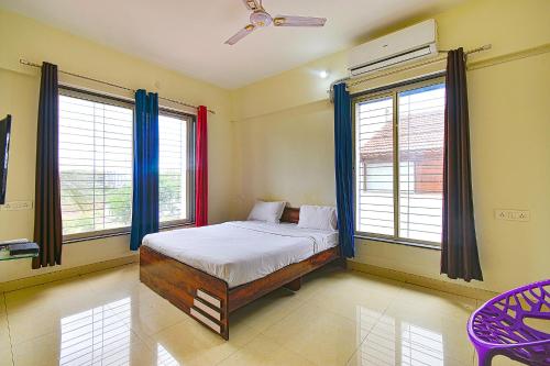 a bedroom with a bed and two windows at FabExpress Golden Leaf Airport in Pune
