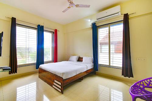 a bedroom with a bed and two windows at FabExpress Golden Leaf Airport in Pune