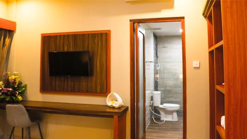 a bathroom with a toilet and a television on the wall at Kubu De Uma in Seminyak