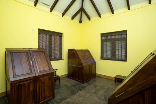a yellow room with two wooden cabinets and windows at Sarth Ayurveda Retreat and Wellness Centre in Sawantwadi