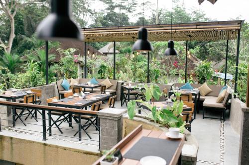 ein Restaurant mit Tischen und Stühlen auf einer Terrasse in der Unterkunft The Compass Rose Ubud in Ubud