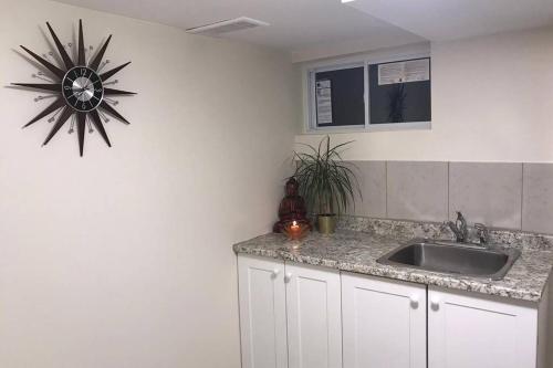 een keuken met een wastafel en een klok aan de muur bij Tastefully decorated spacious apartment Burlington in Burlington