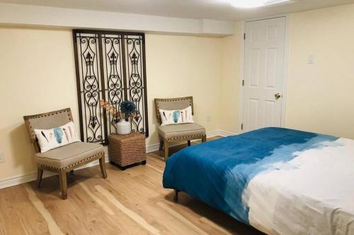 een slaapkamer met een bed en 2 stoelen. bij Tastefully decorated spacious apartment Burlington in Burlington