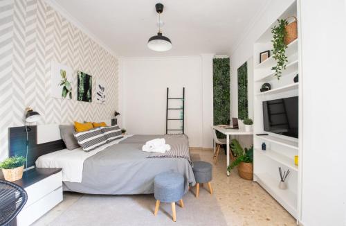 a bedroom with a bed and a desk and a tv at Nordik Rooms Urban - Trinidad "Copenhague" in Málaga