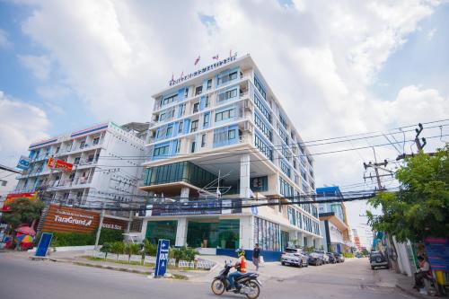 a person riding a motorcycle in front of a building at Taragrand Donmuang Airport Hotel in Thanyaburi