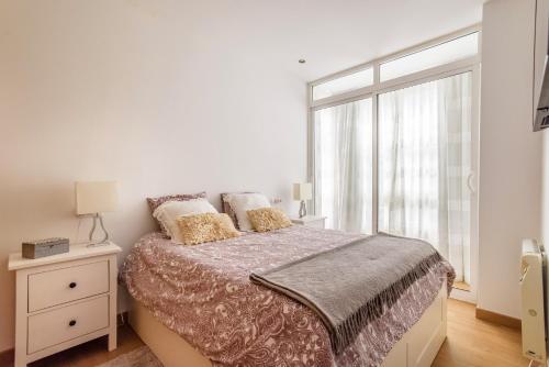 a white bedroom with a bed and a window at Precioso apartamento nuevo en el centro de A Coruña! in A Coruña