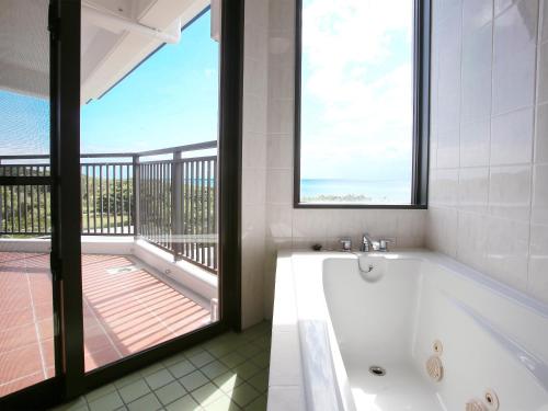 a bath tub in a bathroom with a balcony at Haruhoo Resort ISHIGAKI in Ishigaki Island