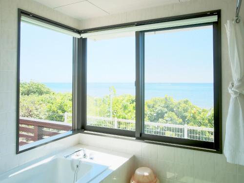 a bathroom with a tub and a large window at Haruhoo Resort ISHIGAKI in Ishigaki Island