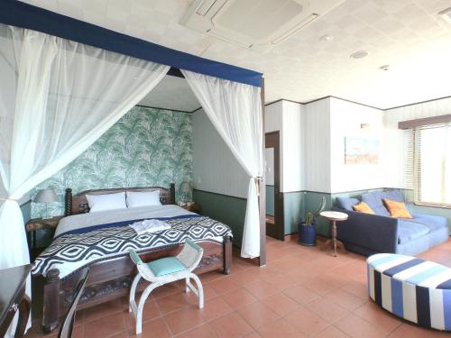 a bedroom with a bed and a chair and a couch at Haruhoo Resort ISHIGAKI in Ishigaki Island