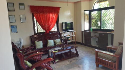 a living room with a table and chairs and a tv at Sofias House Rental in Tagbilaran City