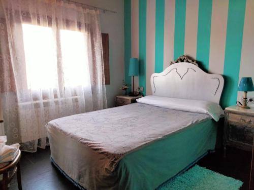 a bedroom with a bed with green and white stripes at En Huerto de Catalina in Fuentes de Béjar