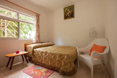 een slaapkamer met een bed, een stoel en een raam bij Jeanny's Apartment in Grand'Anse Praslin