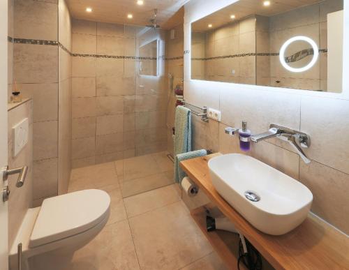 ein Badezimmer mit einem Waschbecken, einem WC und einem Spiegel in der Unterkunft Glühwürmchen Cottage in Oberaudorf
