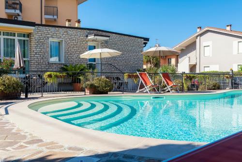 una piscina con 2 sillas y una sombrilla en Residence Campana, en Bardolino