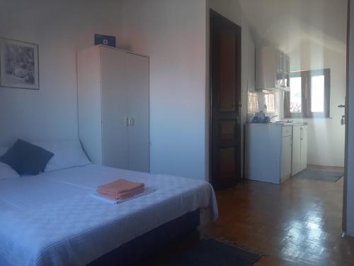 a white bedroom with a bed and a kitchen at Vila Dora Supetar in Supetar