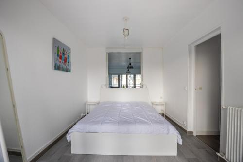 - une chambre blanche avec un lit blanc et une fenêtre dans l'établissement Les Sardines, à Courseulles-sur-Mer