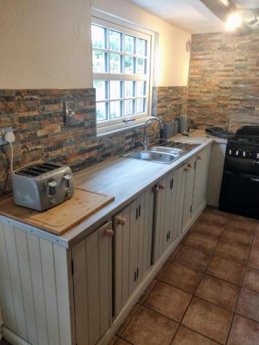 a kitchen with a counter with a sink and a window at 4BR 4 Bathroom Cottage Parking Garden Near St Neots in Saint Neots